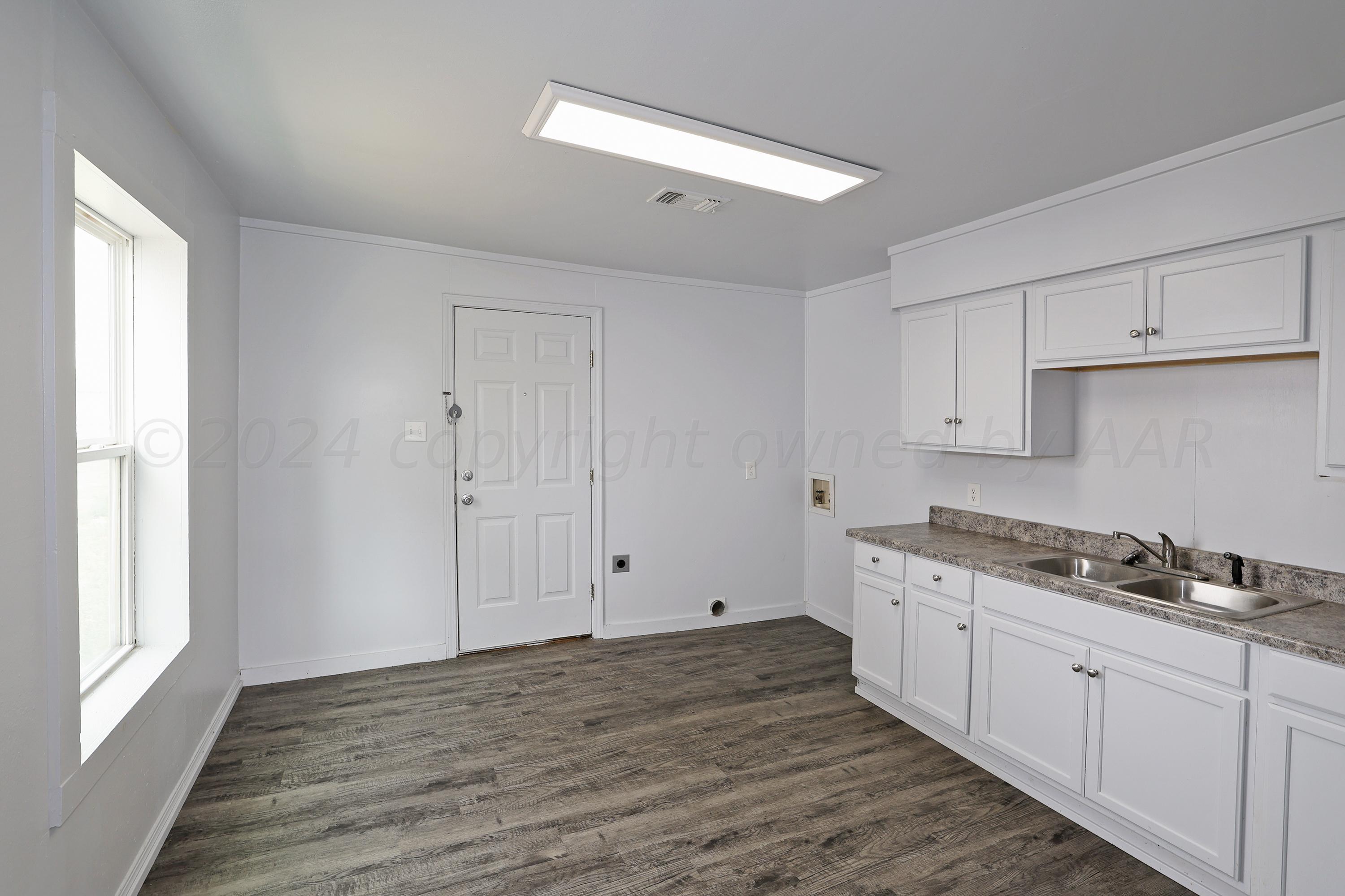 3703 South Monroe Street Amarillo, TX 79110 - Photo 6 of 14 a kitchen with granite countertop a stove a sink and white cabinets with wooden floor