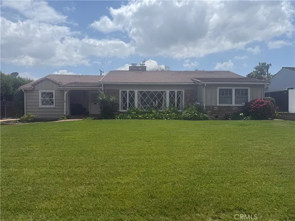 a view of house with a big yard and potted plants
