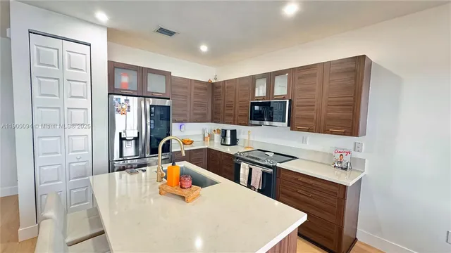 a kitchen with stainless steel appliances a stove a refrigerator a sink a dining table and chairs