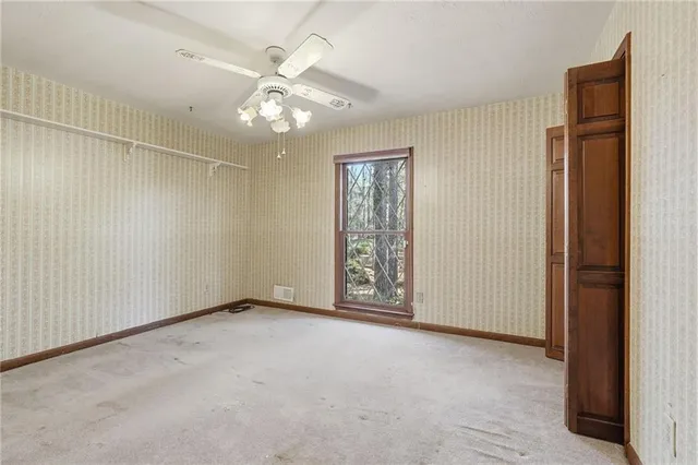an empty room with chandelier fan and windows