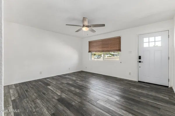 an empty room with wooden floor ceiling fan and windows