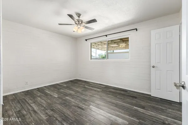 a view of an empty room with wooden floor and a fan