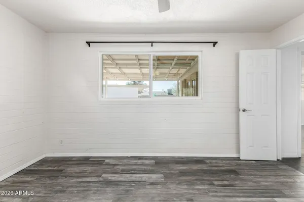 a view of an empty room with wooden floor and a window
