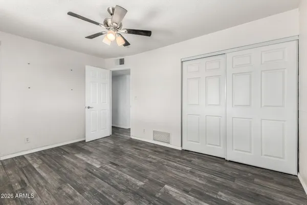 an empty room with wooden floor and ceiling fan