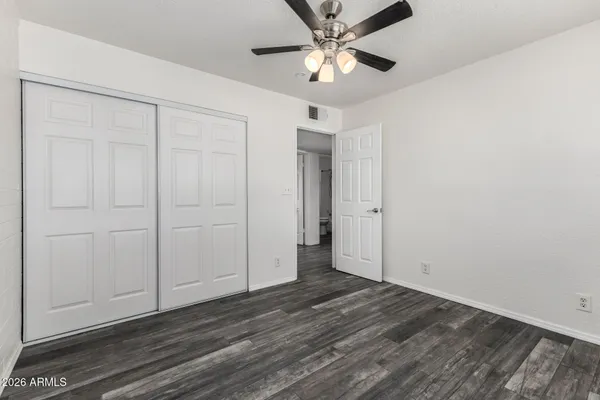 an empty room with wooden floor closet and windows