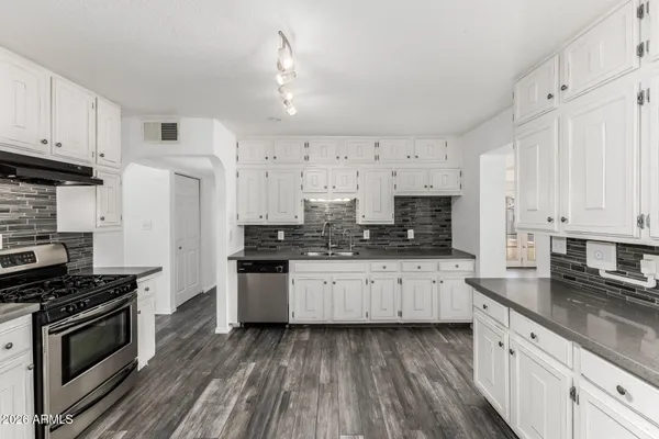 a kitchen with granite countertop a sink stainless steel appliances and cabinets