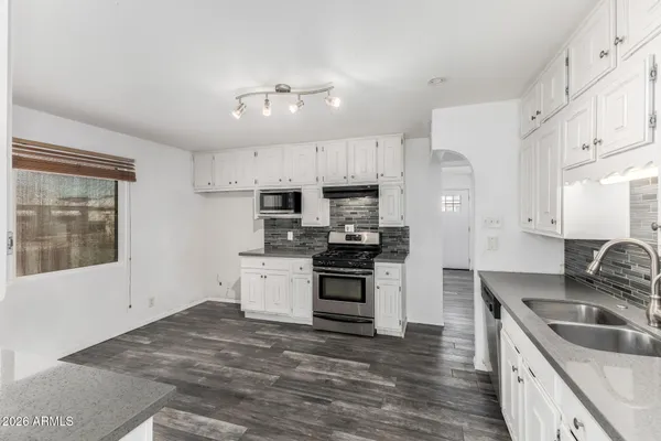 a kitchen with granite countertop a sink stainless steel appliances and cabinets