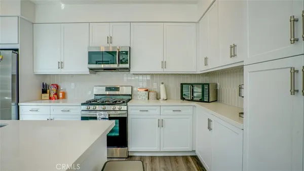 a kitchen with stainless steel appliances a sink stove and white cabinets