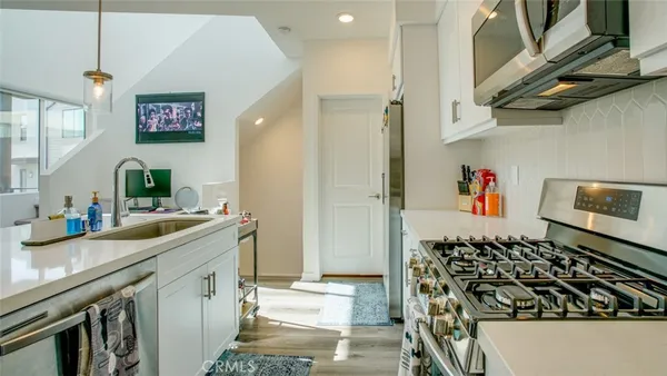a kitchen with stainless steel appliances granite countertop a stove a sink and white cabinets