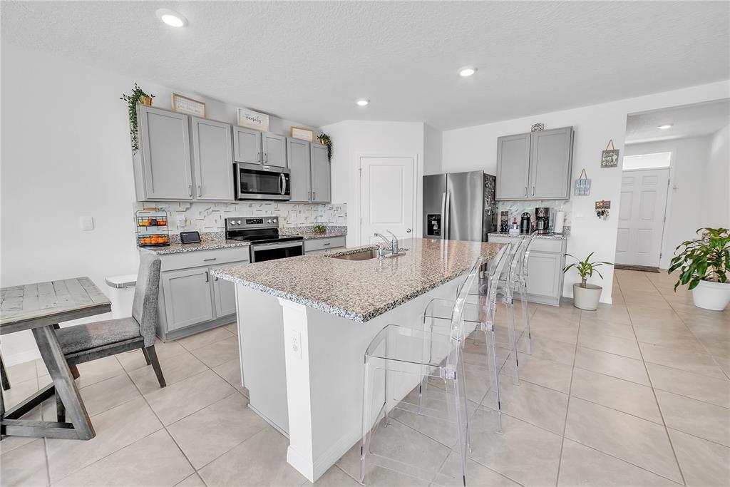 8237 Juning Cove Wesley Chapel, FL 33545 - Photo 15 of 59 a kitchen with stainless steel appliances granite countertop a stove top oven a sink a microwave and a refrigerator