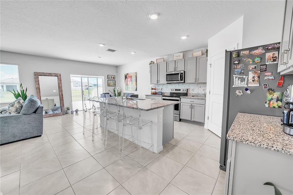 8237 Juning Cove Wesley Chapel, FL 33545 - Photo 17 of 59 a kitchen with stainless steel appliances granite countertop a stove top oven a sink a refrigerator and a granite counter tops