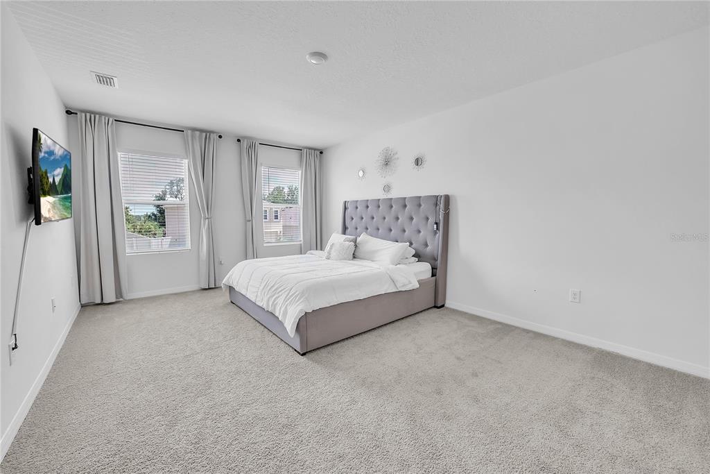 8237 Juning Cove Wesley Chapel, FL 33545 - Photo 32 of 59 a spacious bedroom with a bed and a window