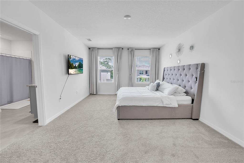 8237 Juning Cove Wesley Chapel, FL 33545 - Photo 33 of 59 a spacious bedroom with a bed and a couch
