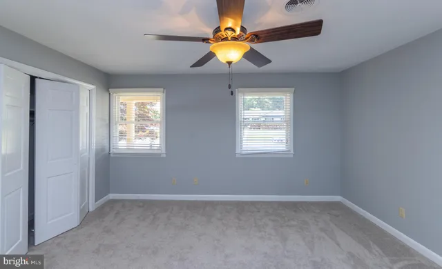 en empty room with windows and chandelier fan