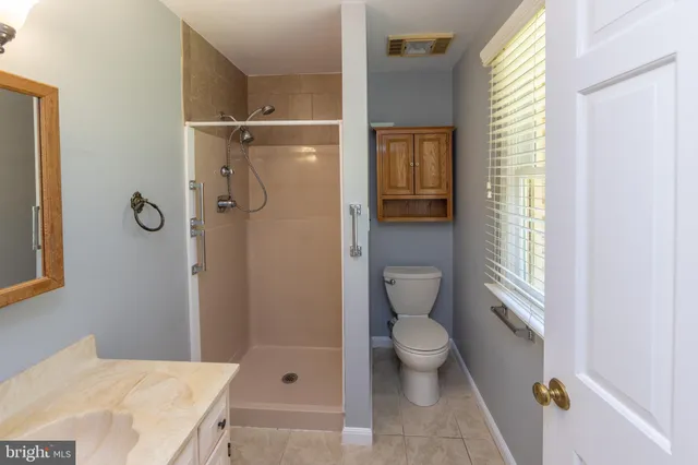 a bathroom with a granite countertop sink a toilet and shower