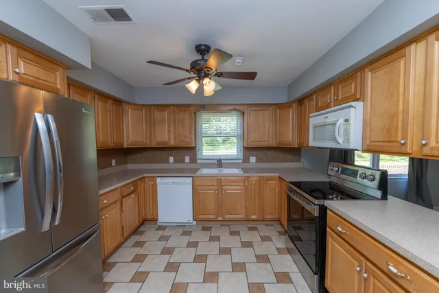 a kitchen with stainless steel appliances granite countertop a sink a stove a refrigerator cabinets and dining table
