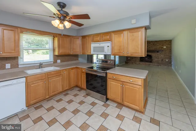 a kitchen with stainless steel appliances a sink a stove a microwave cabinets and a window