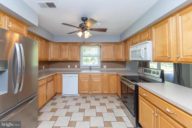 a kitchen with stainless steel appliances granite countertop a refrigerator a sink a stove a microwave and cabinets