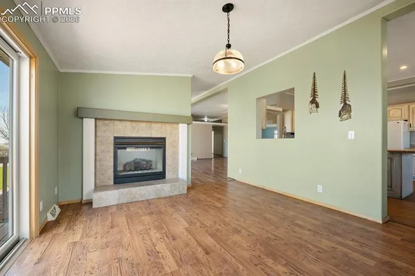 a view of an empty room with wooden floor fireplace and a window