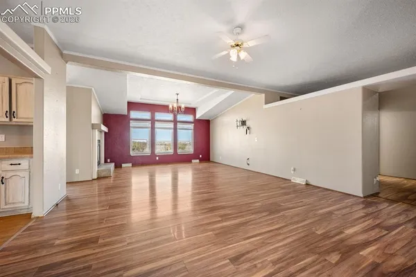 a view of an empty room with window and wooden floor