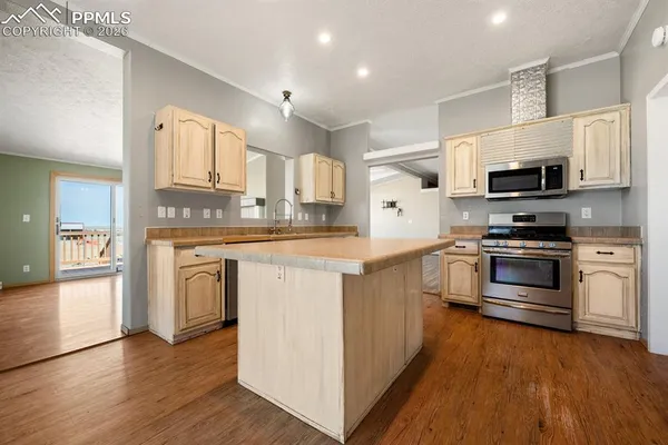 a kitchen with stainless steel appliances a stove top oven a sink a refrigerator white cabinets and wooden floor