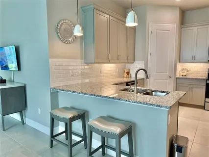 a kitchen with white cabinets and sink