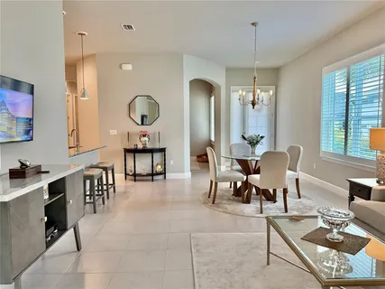 a living room with furniture a chandelier and a dining table