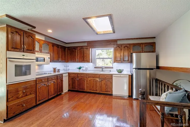 a kitchen with stainless steel appliances granite countertop a sink a stove a refrigerator cabinets and wooden floor