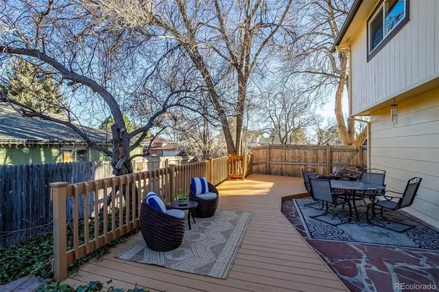 a view of a patio with dining table and chairs with wooden floor and fence