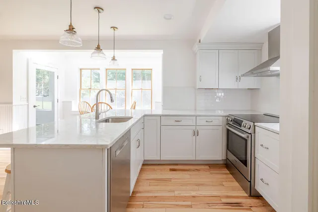 a kitchen with stainless steel appliances granite countertop a sink a stove and a refrigerator