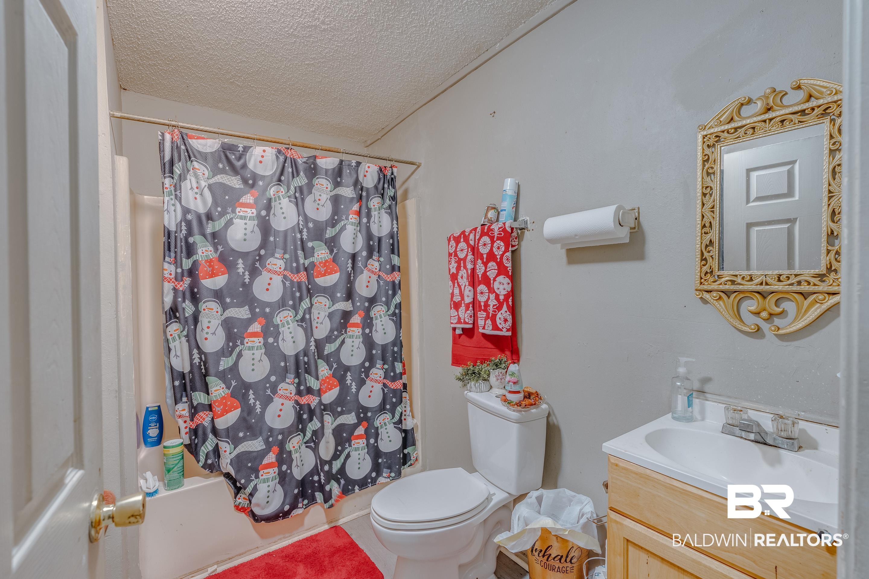 1156 Freeman Street Mobile, AL 36605 - Photo 16 of 22 Bathroom featuring vanity, a textured ceiling, shower / bath combo, and toilet