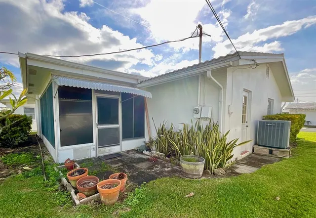 a backyard of a house with table and chairs floor to ceiling window and potted plants