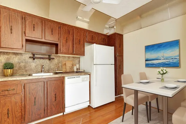 a kitchen with stainless steel appliances granite countertop a refrigerator a sink dishwasher and white cabinets with wooden floor