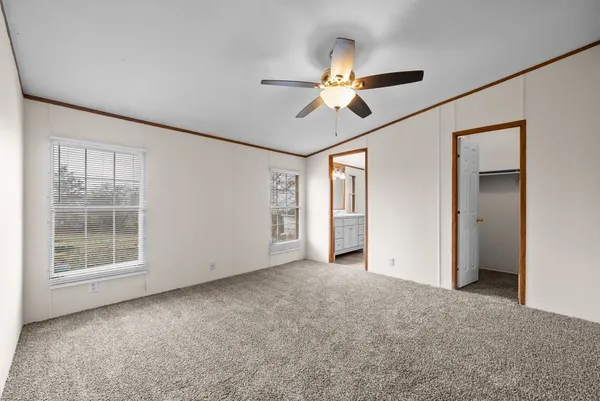 an empty room with windows and fan