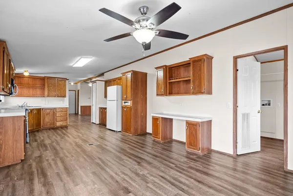 a living room with stainless steel appliances kitchen island hardwood floor and a ceiling fan
