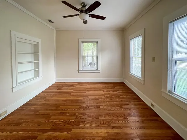 a view of an empty room with a window and wooden floor