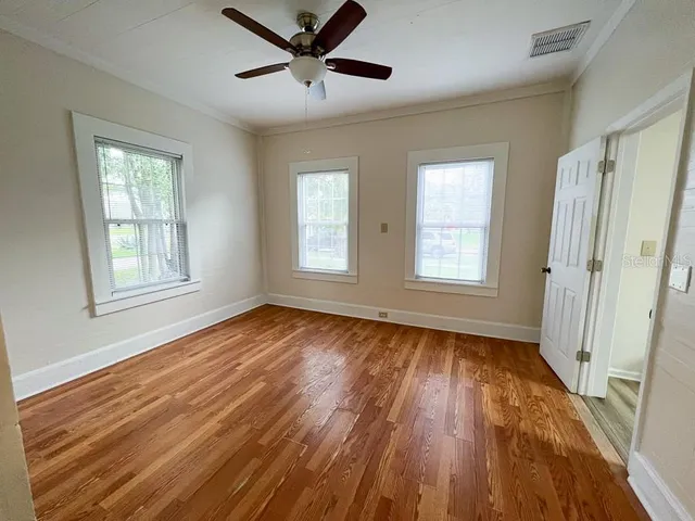 a view of empty room with wooden floor and fan
