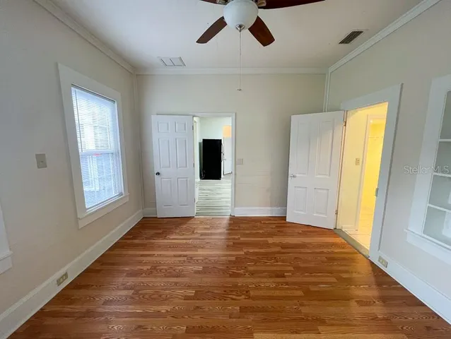 a view of an empty room with window and wooden floor