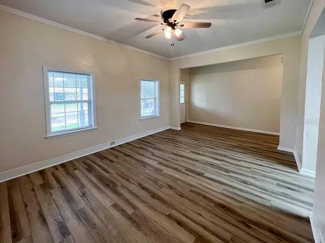 a view of an empty room with wooden floor and a window