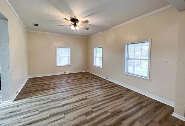 a view of an empty room with wooden floor and a window