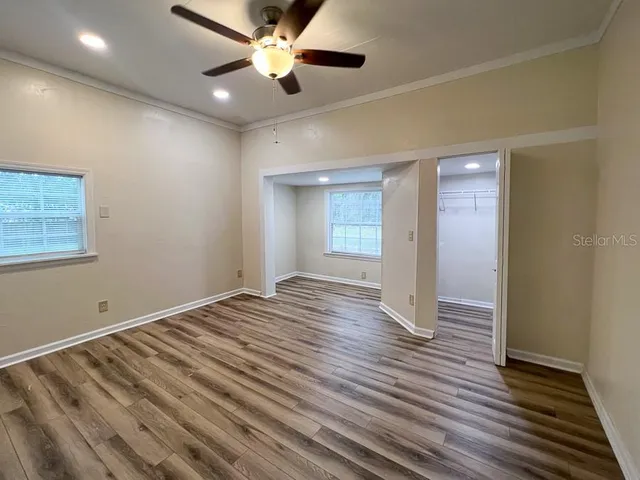 a view of empty room with wooden floor and fan