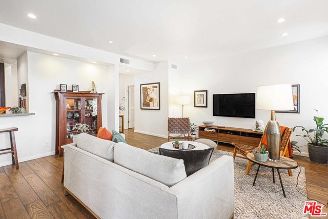 a living room with furniture kitchen view and a flat screen tv