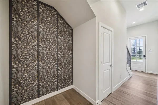 a view of a hallway with wooden floor and closet