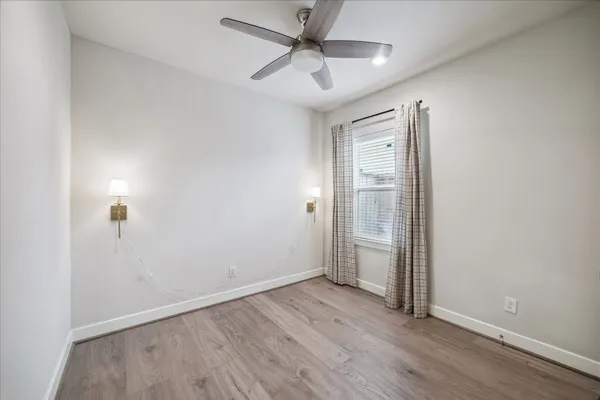 an empty room with wooden floor and ceiling fan