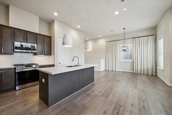 a large kitchen with stainless steel appliances granite countertop a stove a sink and a refrigerator