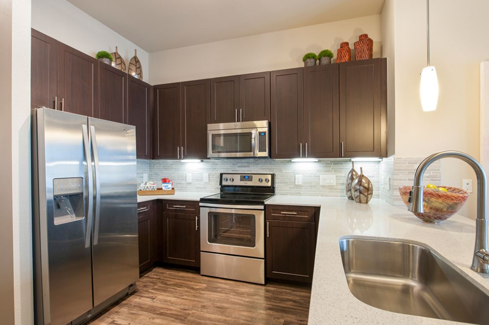 2033 South Gessner Road, Unit 2105 Houston, TX 77063 - Photo 4 of 23 a kitchen with stainless steel appliances wooden cabinets a sink and a refrigerator