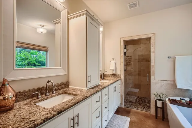 a bathroom with a granite countertop double vanity sink a mirror and a shower