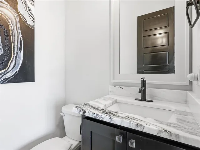 a bathroom with a granite countertop sink a toilet and mirror
