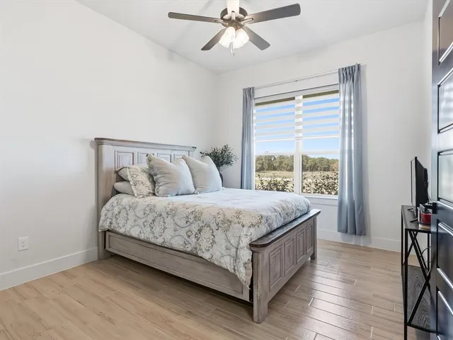 a bedroom with a bed a flat screen tv and a window