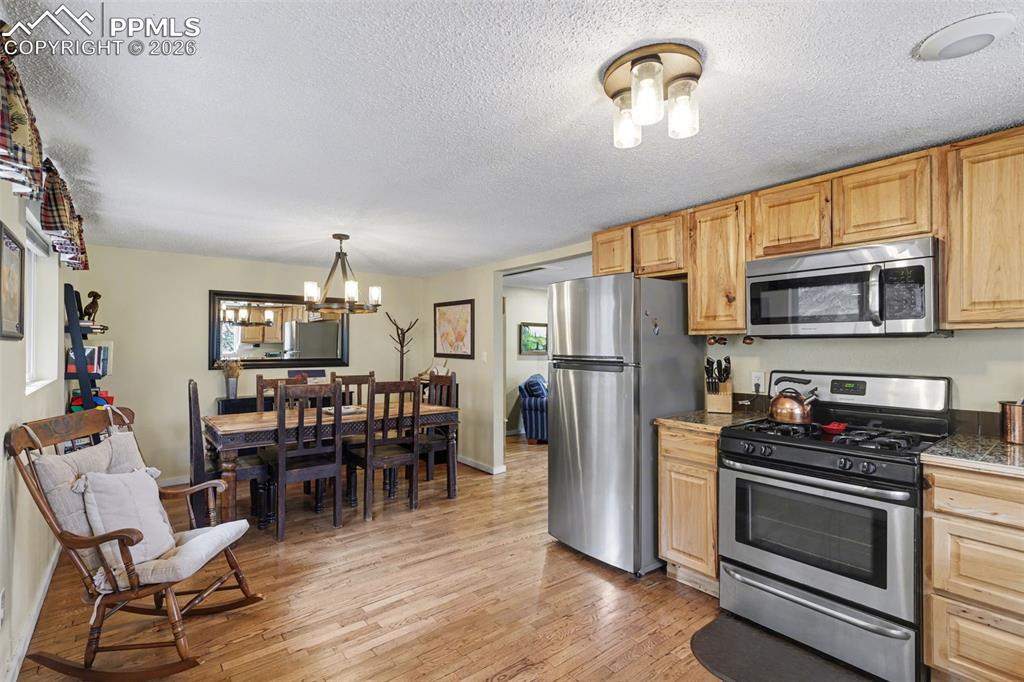 10145 Chipita Park Road Cascade, CO 80809 - Photo 12 of 33 Kitchen featuring stainless steel appliances, light wood-style flooring, hanging lights, a textured ceiling, and light wood finish cabinetry